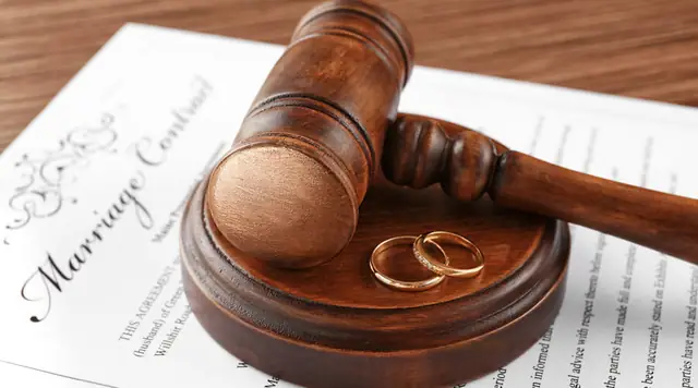 Martelo de juiz e alianças sobre um contrato de casamento